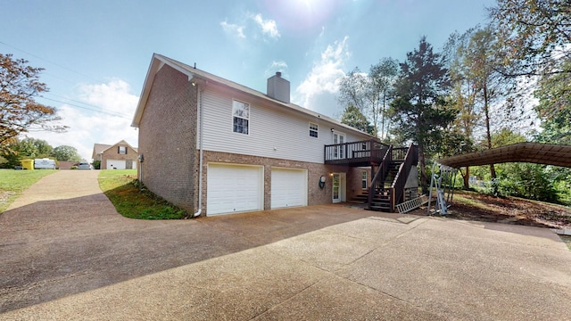 view of side of home featuring stairway, concrete driveway, an attached garage, brick siding, and a chimney