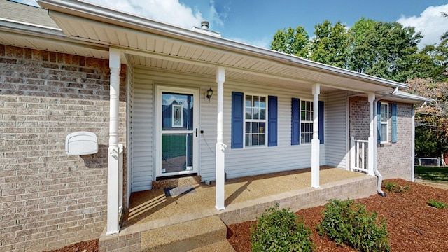 doorway to property with brick siding and covered porch