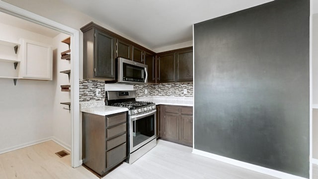 kitchen featuring visible vents, dark brown cabinetry, light countertops, decorative backsplash, and stainless steel appliances