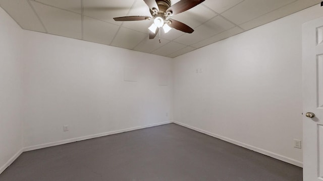 spare room featuring baseboards, a paneled ceiling, concrete flooring, and a ceiling fan