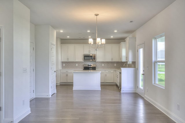 kitchen featuring appliances with stainless steel finishes, wood finished floors, white cabinets, and decorative backsplash