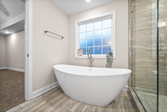 bathroom featuring a soaking tub, baseboards, and a tile shower