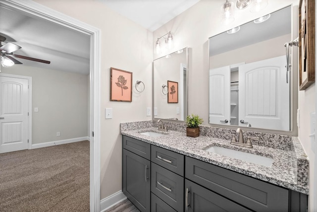 full bath with double vanity, baseboards, ceiling fan, and a sink