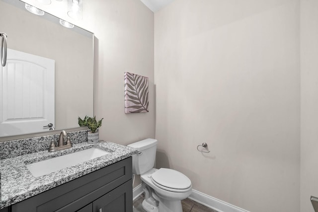 half bath with toilet, vanity, and baseboards