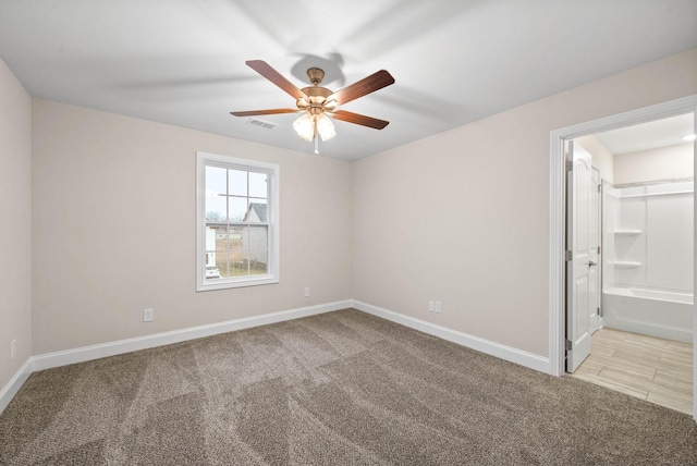 carpeted spare room with baseboards, visible vents, and ceiling fan