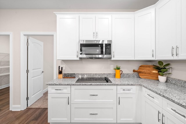 kitchen with white cabinetry, stainless steel microwave, black electric cooktop, and dark wood-type flooring