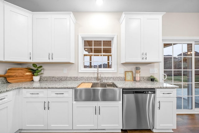 kitchen with stainless steel dishwasher, white cabinets, dark wood finished floors, and a sink