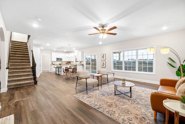 living room with dark wood-type flooring, recessed lighting, stairway, baseboards, and ceiling fan