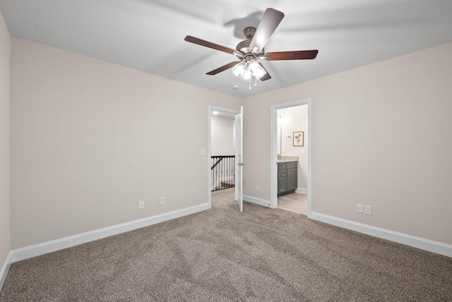 unfurnished bedroom with light colored carpet, ensuite bath, baseboards, and ceiling fan