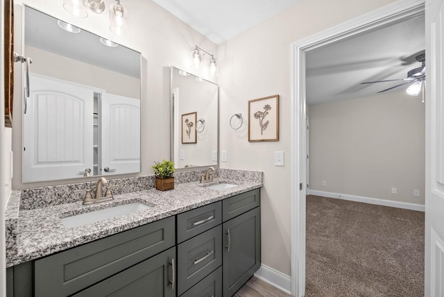 full bathroom with double vanity, baseboards, a ceiling fan, and a sink