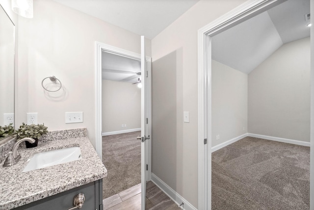 bathroom with vanity, lofted ceiling, and baseboards