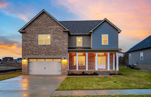 traditional-style house with brick siding, a front lawn, covered porch, a garage, and driveway