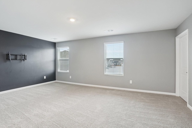 carpeted spare room featuring a healthy amount of sunlight, visible vents, and baseboards