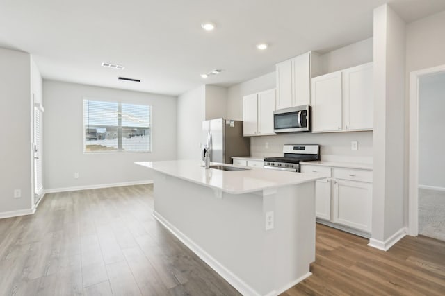 kitchen with visible vents, appliances with stainless steel finishes, a kitchen island with sink, light countertops, and white cabinetry