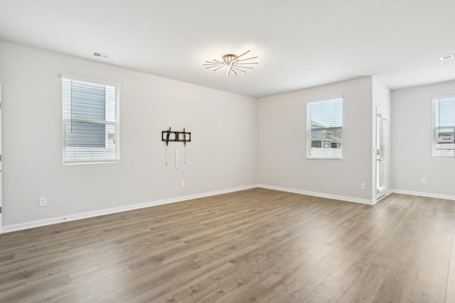 unfurnished room with visible vents, baseboards, and wood finished floors