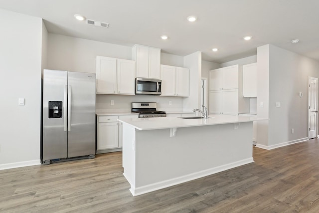 kitchen with visible vents, white cabinets, light countertops, appliances with stainless steel finishes, and a center island with sink