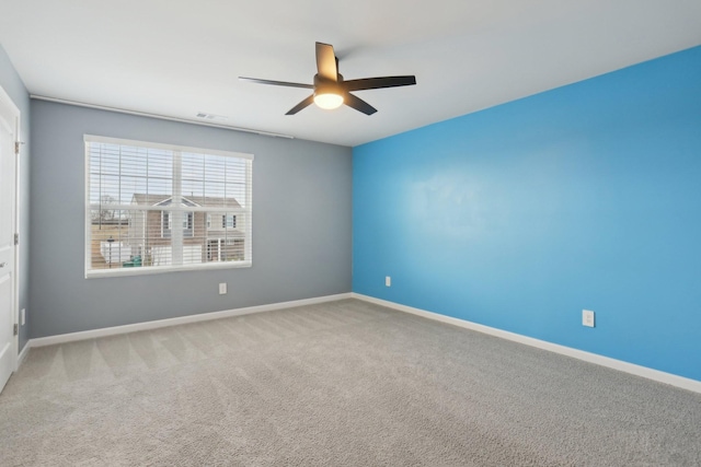 carpeted spare room with a ceiling fan, visible vents, and baseboards