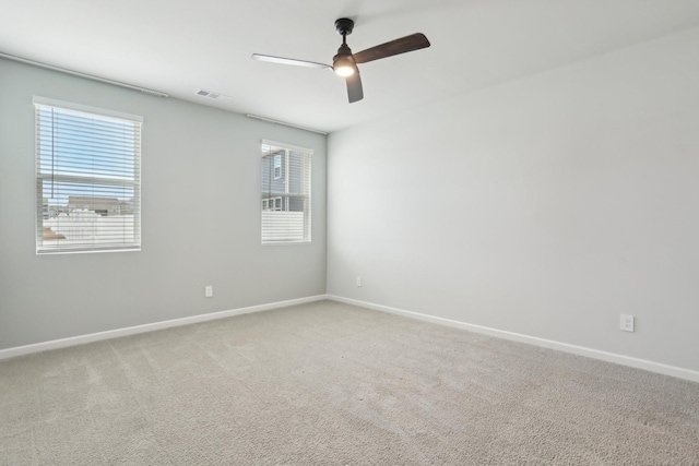 empty room featuring light colored carpet, visible vents, ceiling fan, and baseboards