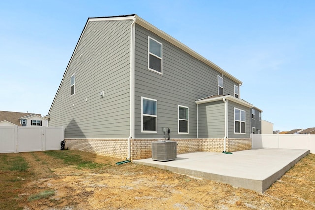 rear view of property with a patio, a gate, fence, cooling unit, and brick siding