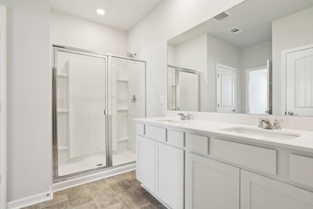 bathroom with double vanity, a stall shower, a sink, and visible vents