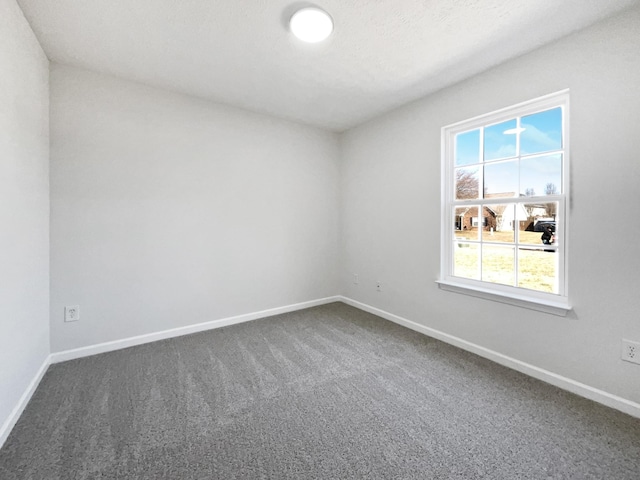 spare room with dark carpet and baseboards