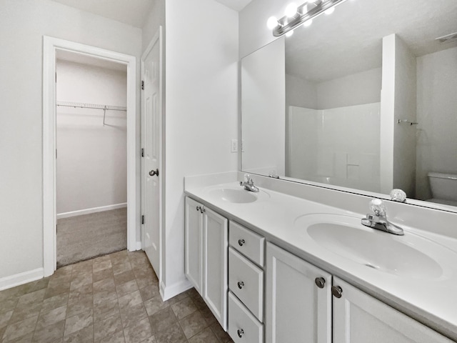 full bathroom with double vanity, baseboards, toilet, and a sink