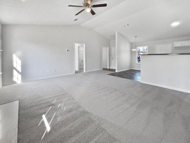 unfurnished living room with visible vents, baseboards, lofted ceiling, carpet flooring, and ceiling fan with notable chandelier