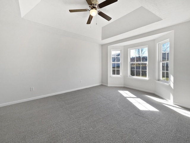 carpeted spare room featuring baseboards, a tray ceiling, and a ceiling fan