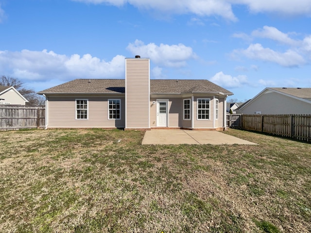 back of property with a patio area, a fenced backyard, a chimney, and a lawn