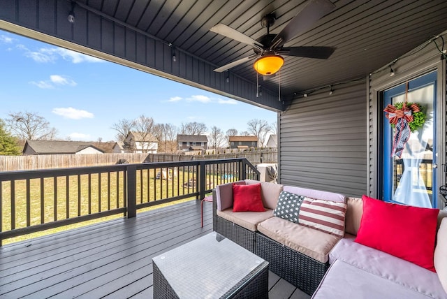 wooden terrace featuring a fenced backyard, an outdoor hangout area, a ceiling fan, a lawn, and a residential view