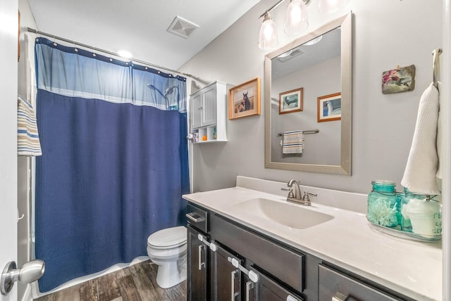 full bathroom featuring curtained shower, toilet, wood finished floors, vanity, and visible vents