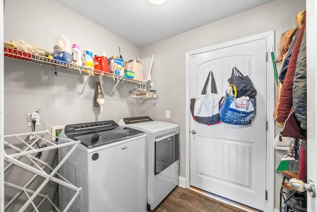 clothes washing area with laundry area, a textured ceiling, washer and clothes dryer, and dark wood-style flooring