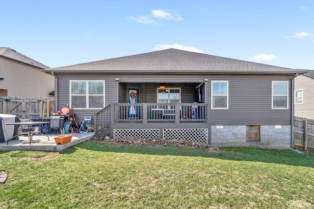 rear view of property with a shingled roof, fence, crawl space, a lawn, and a patio area