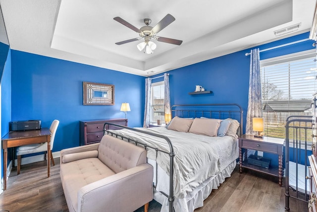 bedroom featuring visible vents, a raised ceiling, and wood finished floors