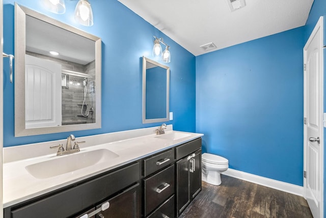 full bathroom featuring wood finished floors, a sink, visible vents, and a shower stall