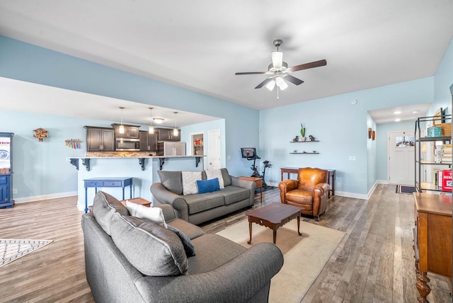 living room with a ceiling fan, light wood-type flooring, and baseboards