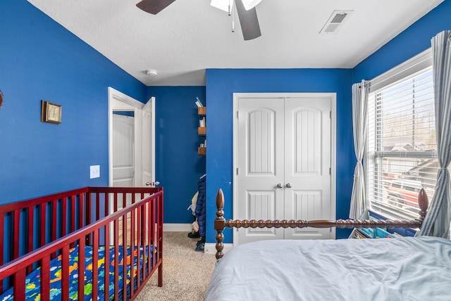 carpeted bedroom featuring a closet, visible vents, ceiling fan, and baseboards