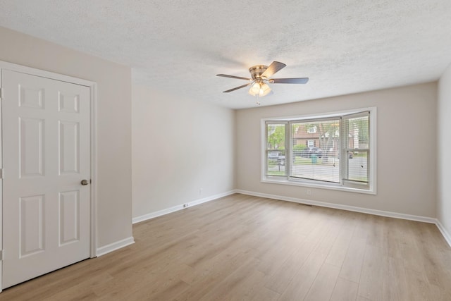 unfurnished room with ceiling fan, a textured ceiling, light wood-type flooring, and baseboards