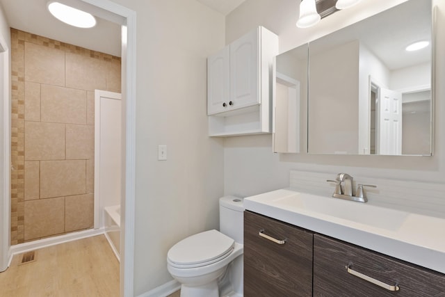 full bath with toilet, wood finished floors, visible vents, vanity, and walk in shower