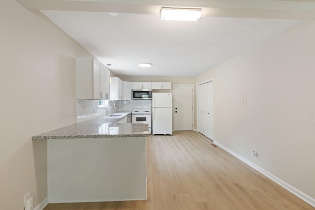 kitchen with white appliances, light wood finished floors, a sink, light stone countertops, and backsplash