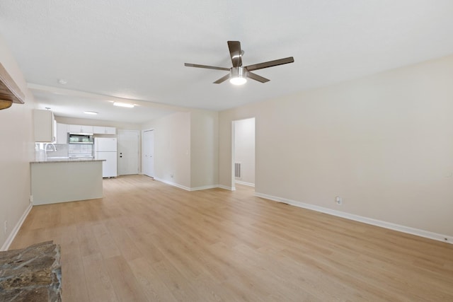 unfurnished living room featuring a ceiling fan, light wood-style flooring, and baseboards