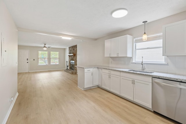 kitchen with white cabinets, a peninsula, stainless steel dishwasher, light wood-style floors, and a sink