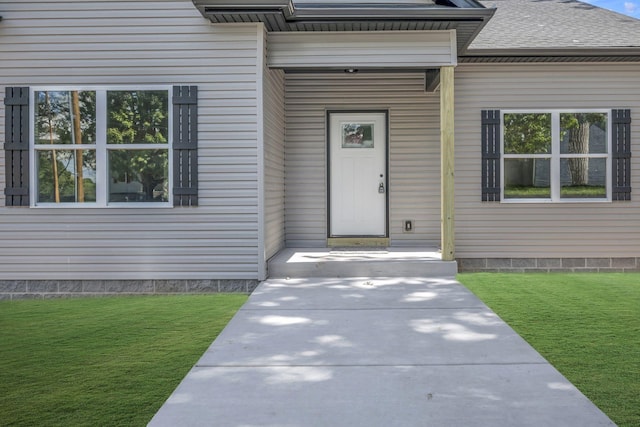 doorway to property with roof with shingles and a lawn