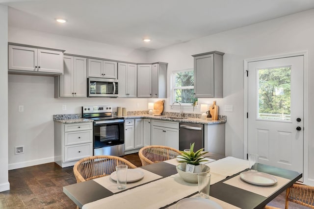 kitchen with dark wood finished floors, stainless steel appliances, recessed lighting, gray cabinets, and baseboards