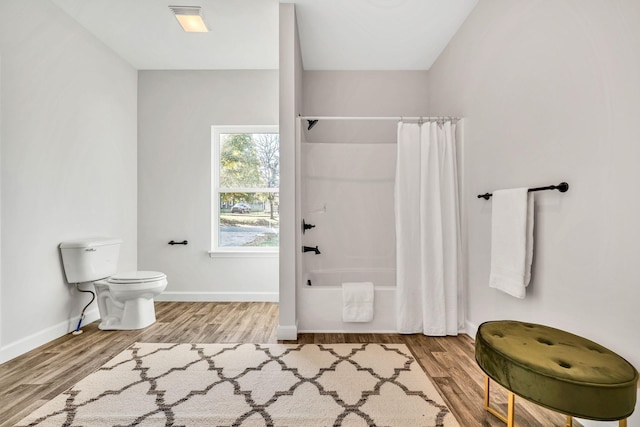 full bathroom with shower / bath combination with curtain, wood finished floors, toilet, and baseboards