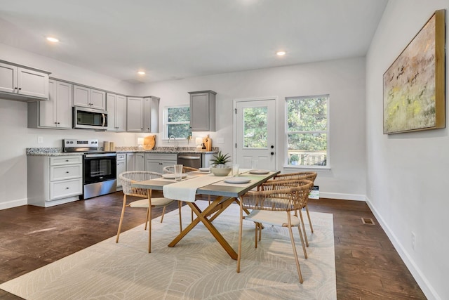 kitchen with baseboards, light stone counters, stainless steel appliances, gray cabinetry, and recessed lighting