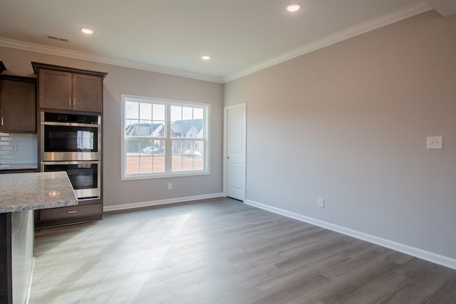 interior space featuring double oven, ornamental molding, backsplash, and baseboards