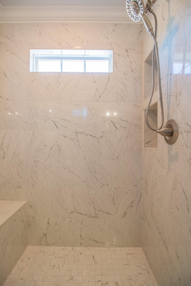 bathroom with ornamental molding, a tile shower, and a wealth of natural light