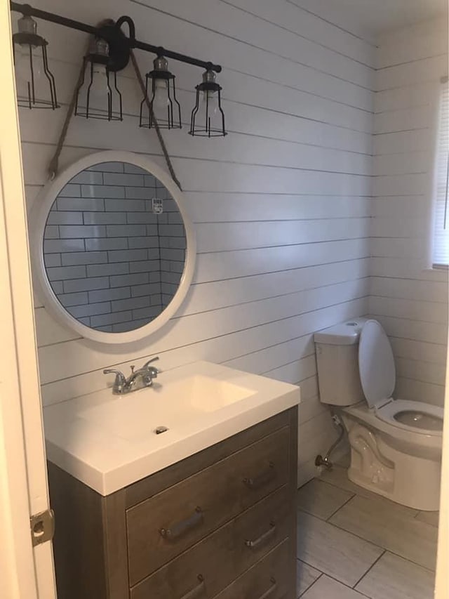 half bath with tile patterned flooring, vanity, and toilet