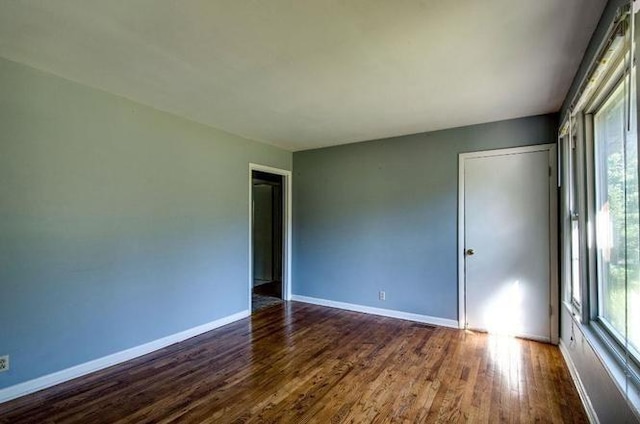 empty room with baseboards and dark wood finished floors